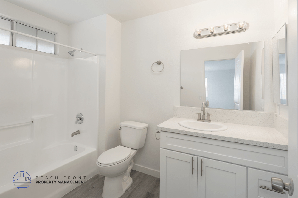 A white bathroom with a toilet, sink, and mirror.